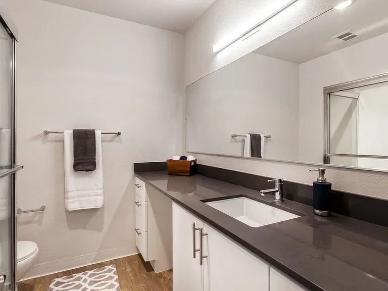Renovated Package I bathroom with dark grey countertop, white cabinetry, and hard surface flooring