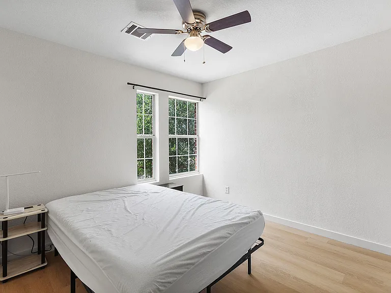 Bedroom with two windows, ceiling fan, and durable wood-look flooring with space for a full or queen bed.