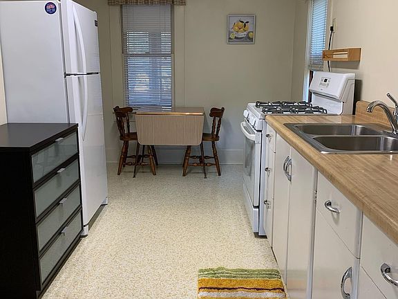 Kitchen and dining area with ceiling fan, frost free refrigerator and gas range.