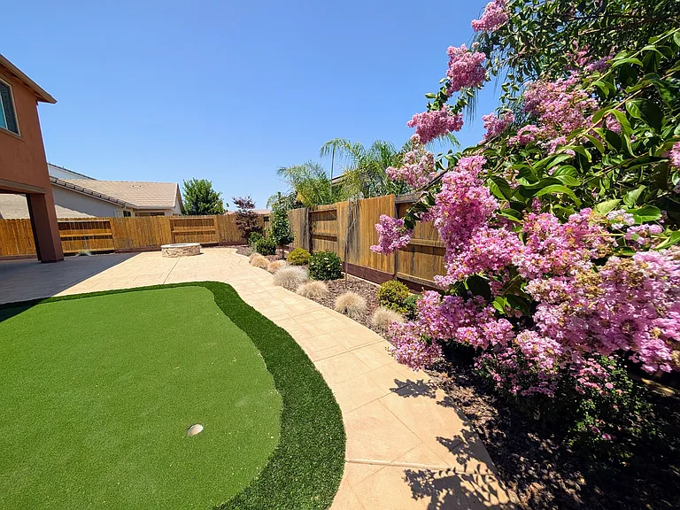 Enjoy vibrant landscaping and lush greenery in your private backyard sanctuary. Featuring a high-quality putting green and colorful flowering trees, this space provides a tranquil, picturesque backdrop for your outdoor living.