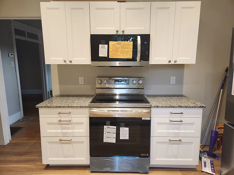 Brand new kitchen includes granite countertops, electric range and microwave.