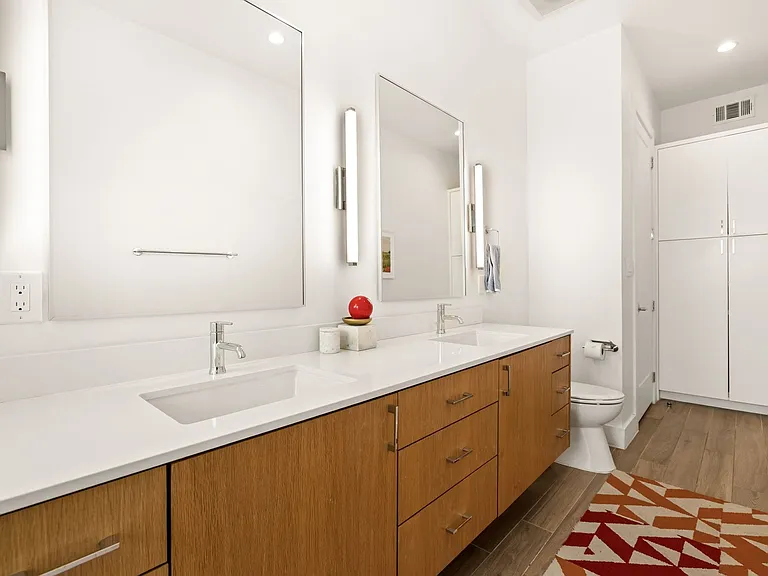 Double vanity with wood-finish cabinetry, integrated sinks, and polished chrome fixtures