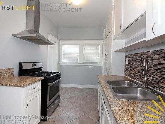 Kitchen with Caesar stone counters, stove, refrigerator, built-in storage cabinets and space for a small table & chairs