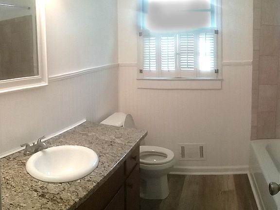 Hall bath with granite countertops and tiled shower.