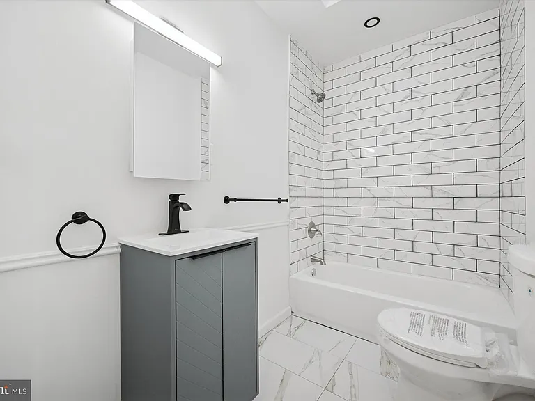 Renovated bath with tiled tub/shower surround, updated vanity with storage, and modern fixtures for easy daily use.