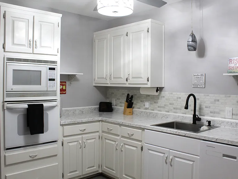A spacious and bright kitchen with lots of cabinets, a ss sink, dishwasher, oven/microwave and full-sized fridge.