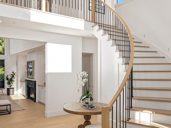 Grand entry with a sprawling custom curved staircase with open solid white oak treads.>