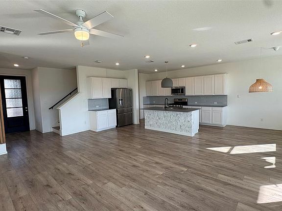 Kitchen with open floor plan, dark countertops, recessed lighting, stainless steel appliances, and white cabinetry