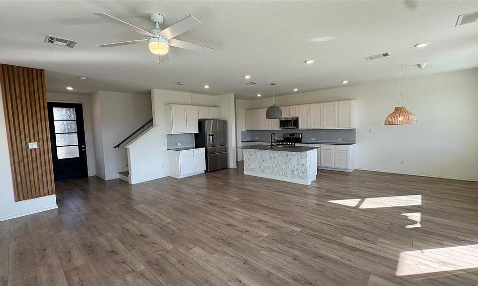 Kitchen with open floor plan, dark countertops, recessed lighting, stainless steel appliances, and white cabinetry