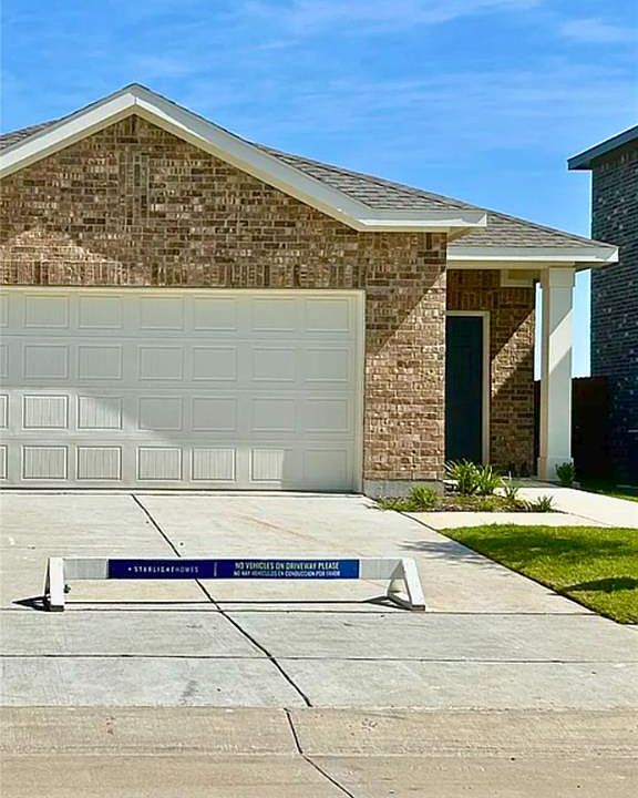 Ranch-style house with brick siding, driveway, roof with shingles, and a garage