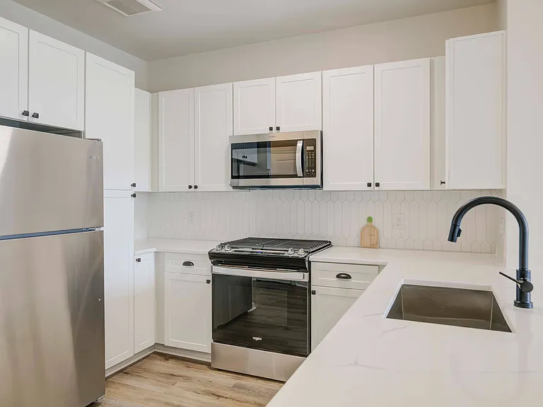 White cabinetry, backsplash, and stainless steel appliances