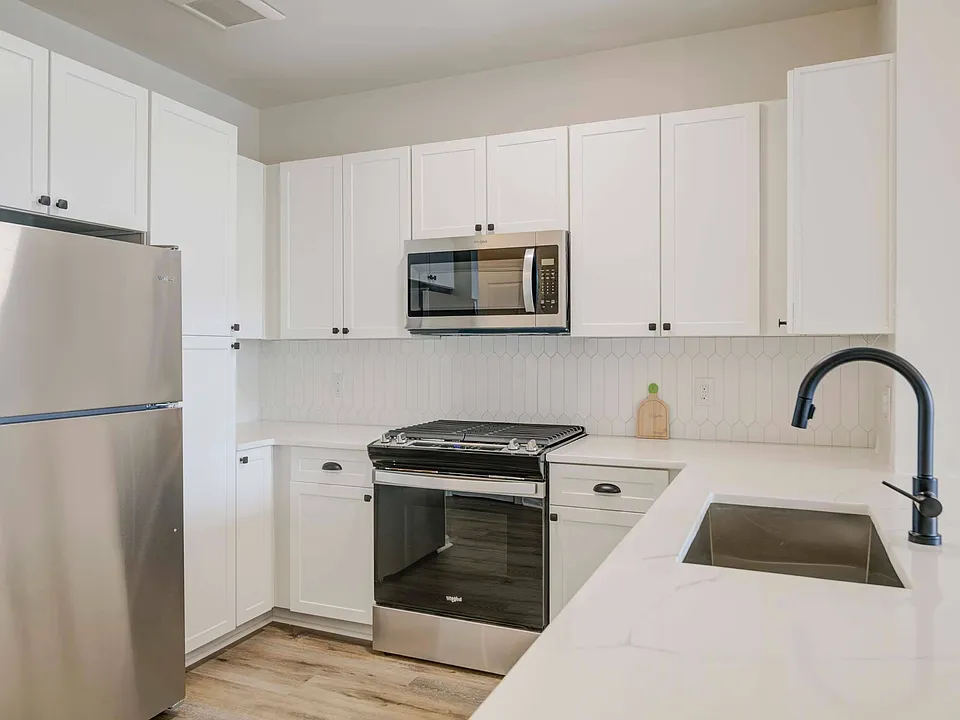 White cabinetry, backsplash, and stainless steel appliances