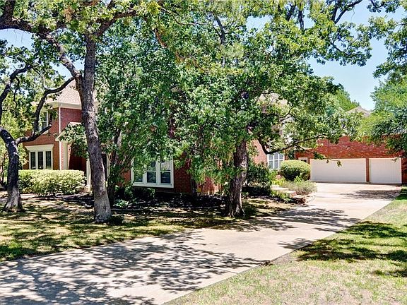 Beautifully landscaped front yard with a long driveway leading to a detached 3 car garage.