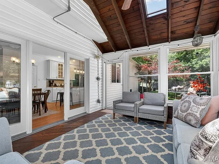 Sunroom featuring a vaulted wood-finish ceiling, exposed beams, and multiple skylights