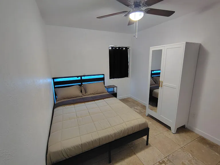 Furnished bedroom with a full bed, ceiling fan, tile flooring, and a wardrobe for convenient in-room storage.