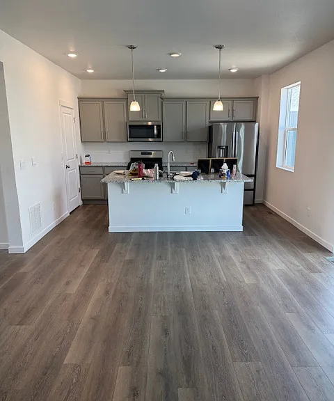 Open kitchen and great room with granite island countertop and stainless steel appliances
