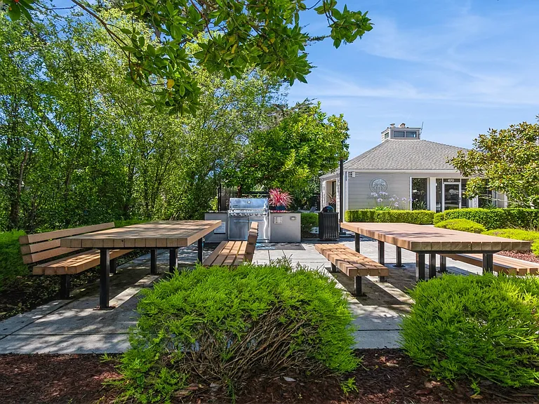Host a barbecue at the outdoor lounge featuring a stainless steel gas grill and picnic tables