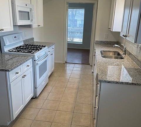 Large galley kitchen with new appliances, granite countertops, and gas stove