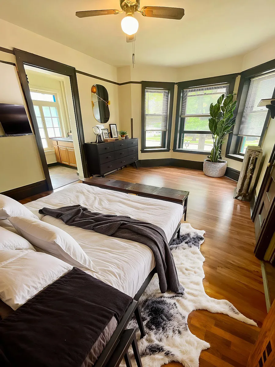 Bright and inviting bedroom with elegant wooden flooring, large windows, and chic decor, creating a serene and stylish sanctuary. - Cross Apartments
