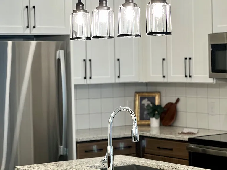Granite kitchen counters with farmhouse sink and stainless steel appliances.