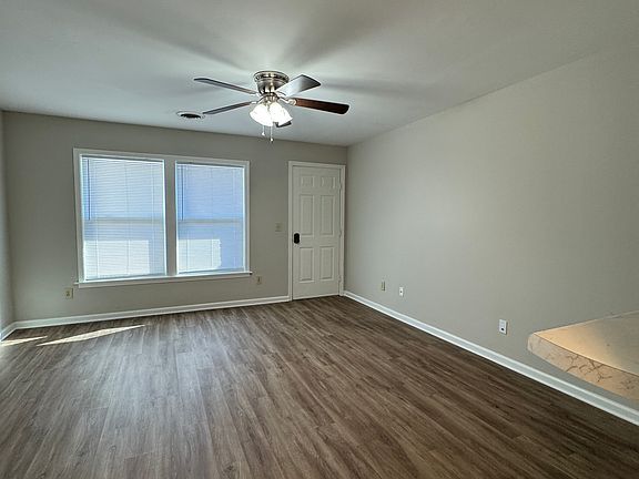 Living room area with ceiling fan and door leading out to the deck