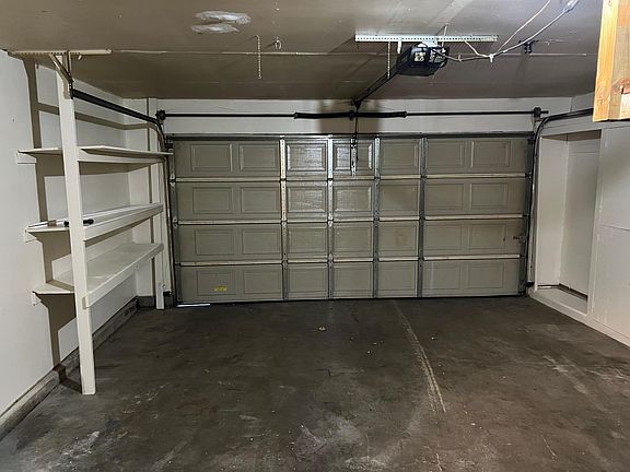 Freshly painted garage with shelves, overhead door operator.