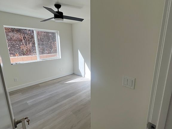 Bedroom 2 with large bright window, ceiling fan and AC.