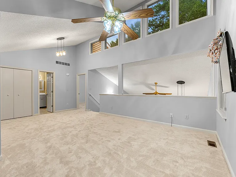 Upstairs living room. Large windows with beautiful pine tree views, opening to the downstairs living room. Doors on the left are utility room with AC, bathroom with a tub, and the second bedroom.