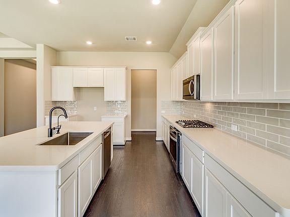 Kitchen with a walk in pantry featuring white cabinets, white countertops and modern subway tile bac