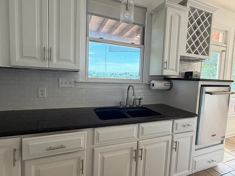 Whip up meals while catching lake views from the kitchen sink_soft white cabinets, dark quartz counters for easy cleanup, and that dreamy water view just over the counter.