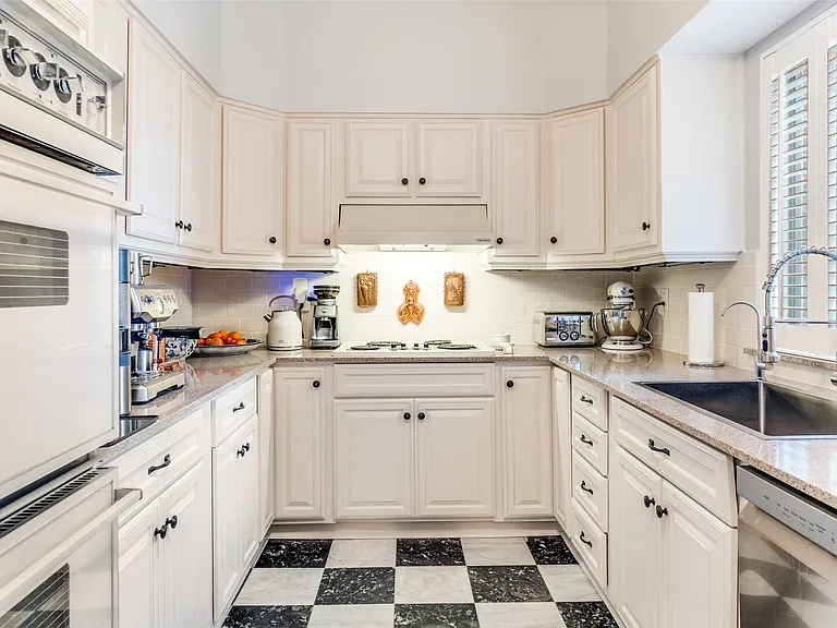 U-shaped kitchen featuring white cabinetry, granite countertops, and a black and white checkered tile floor