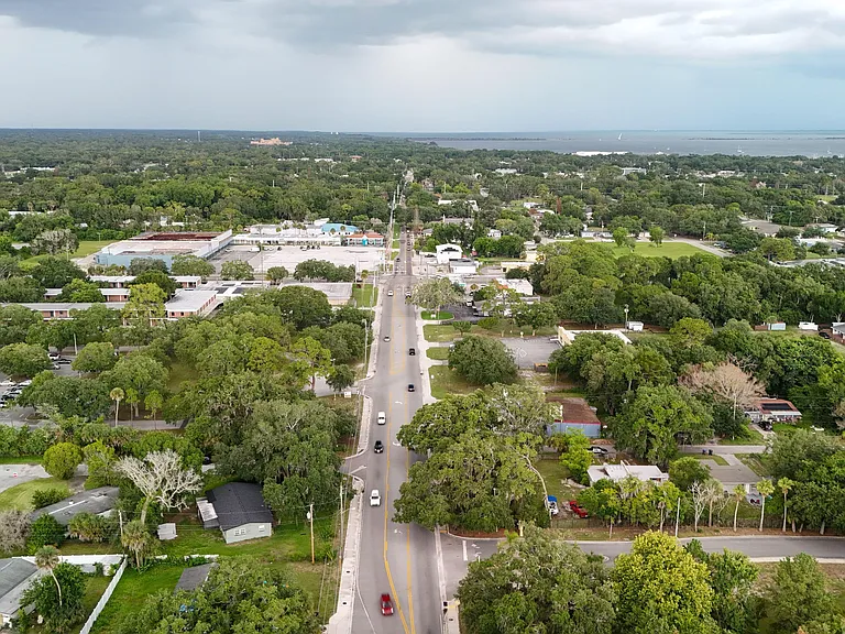 Aerial view of a tree-lined neighborhood with convenient access to main roads and nearby waterfront amenities.