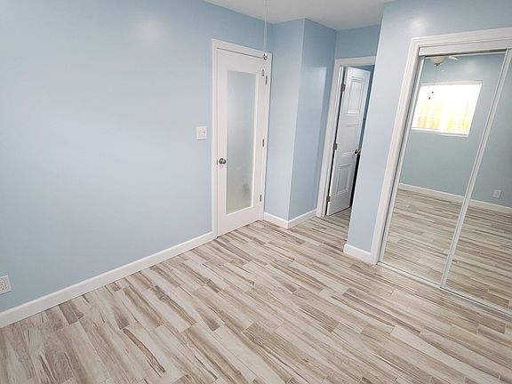 Bedroom features mirrored closet doors and ceiling fan.