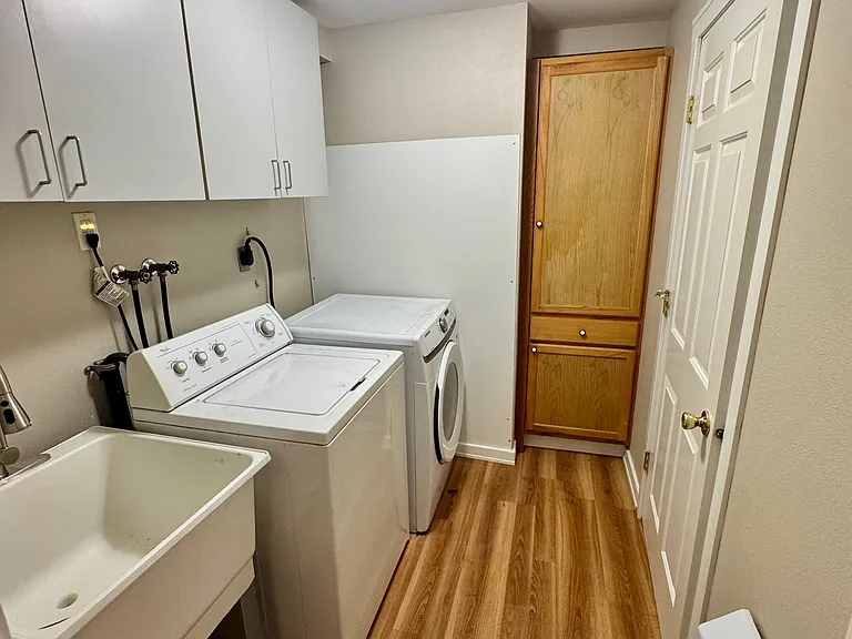 Full sized laundry machines with storage and deep wash sink.