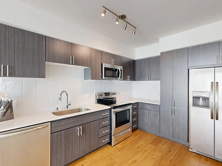Apartment Kitchen with Stainless Steel Appliances and Wood-Style Flooring.