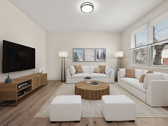 Bright and inviting apartment living room with modern decor, featuring large windows, cozy white sofas, and a stylish wooden coffee table, perfect for relaxation and entertainment.