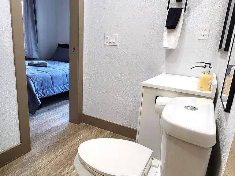 New half bath with vanity sink, and easy-care flooring, conveniently located near the bedroom.