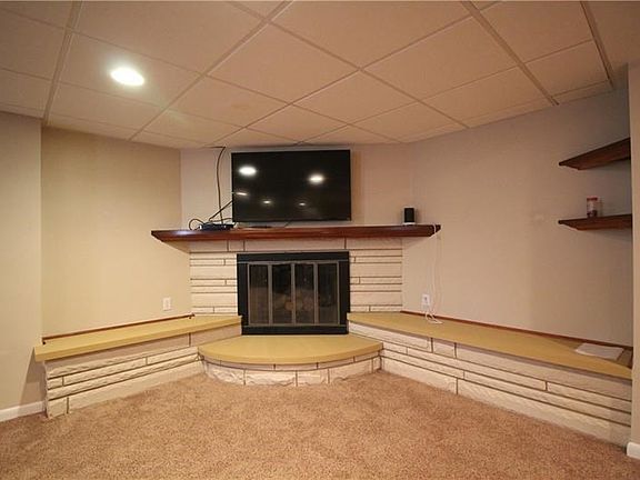 A modern functional fireplace with decorative shelving provides a focal point for cozy movie nights or watching the big game.