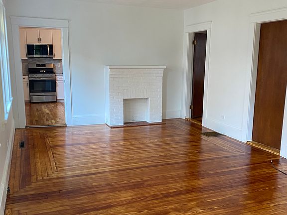 Living room showing the brick fireplace (not functional), entry to newly renovated kitchen, and doors to two bedrooms