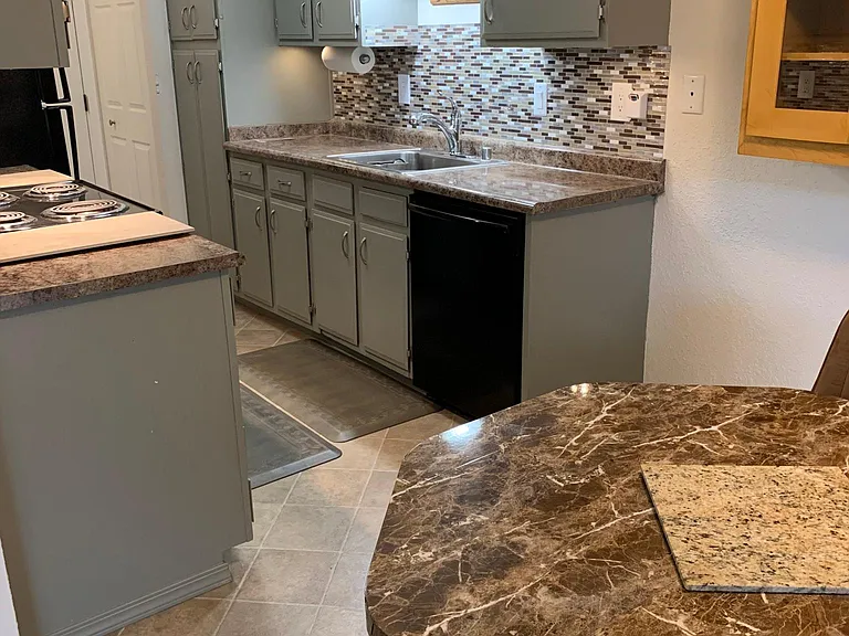 Hanging light above sink as well as ceiling light, and under cabinet lights, sectional paper towel holder, lineolum flooring in kitchen and dinette.