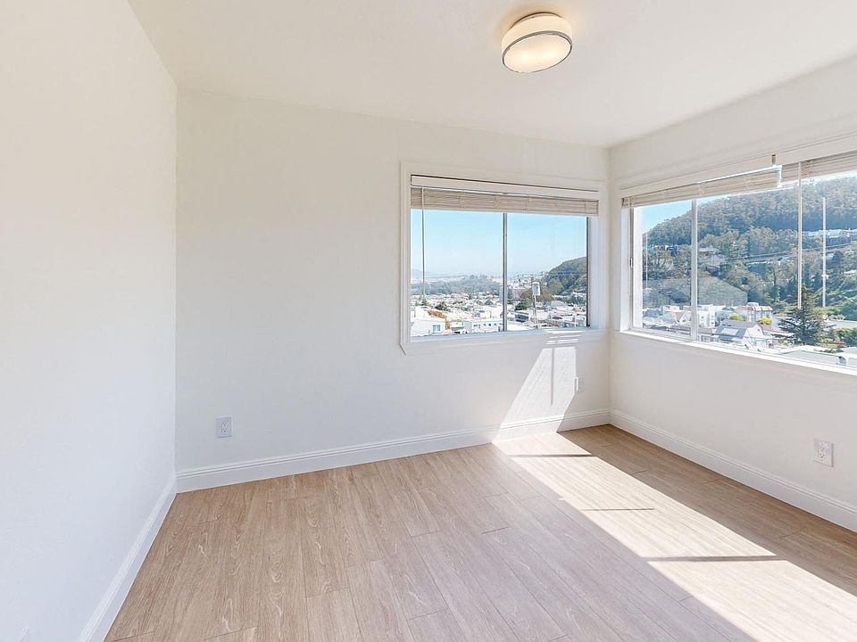 Sunlit room with a large window and a wood-like flooring