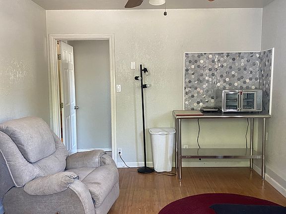 Living area, bamboo flooring, kitchenette, door to bathroom and bedroom.