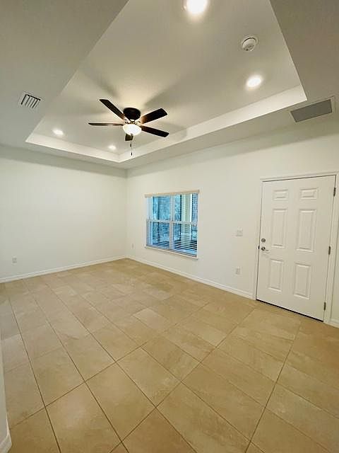 Large family/living room space featuring tray ceilings, ceiling fans and extra storage space.