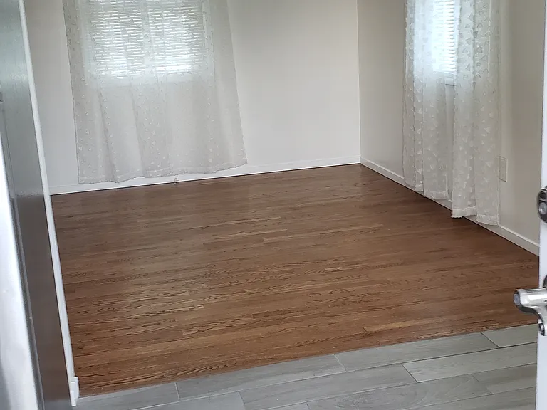 Looking towards corner of front room, while standing in dining area, next to kitchen.
