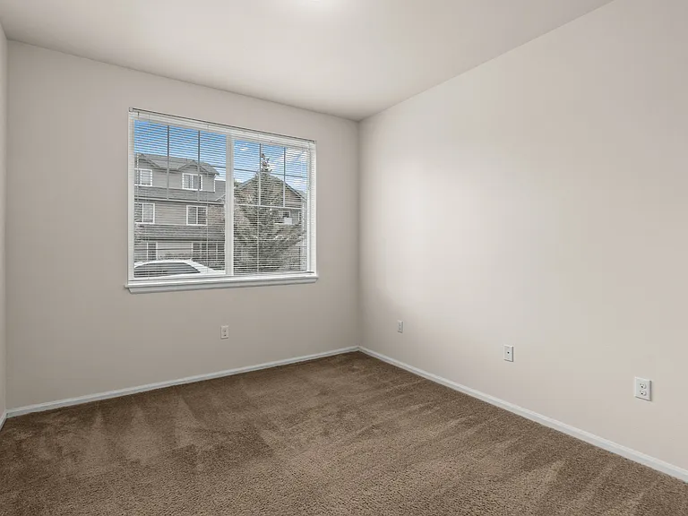 A cozy bedroom with soft carpeting and natural light from a large window. A cozy bedroom with soft carpeting and natural light from a large window.