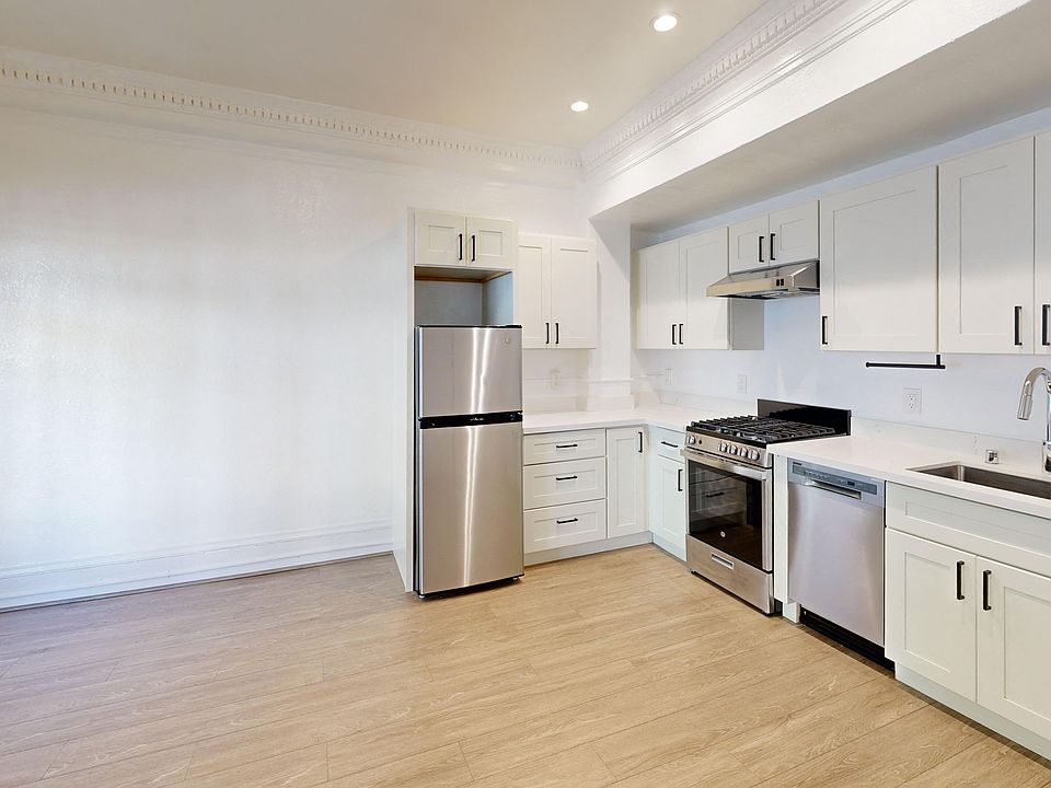 Kitchen with multiple cabinets, refrigerator, stove, range hood, and sink