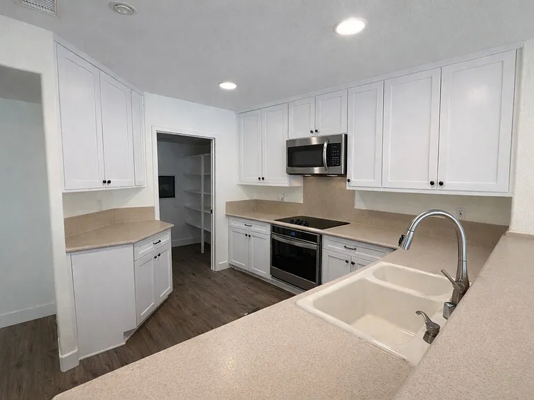 Spacious kitchen with new stainless steel appliances, new white cabinets, and a kitchen bar.