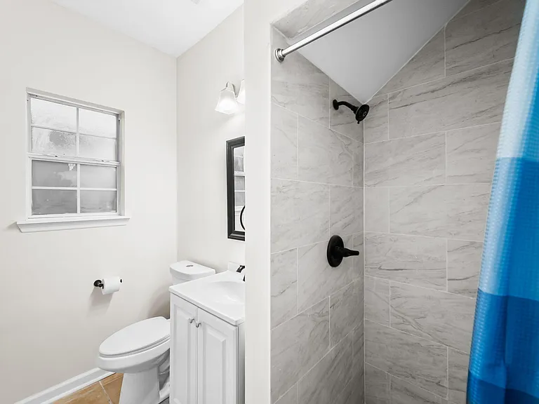 Clean bathroom with a tiled walk-in shower, vanity storage, and a window for added ventilation and light.