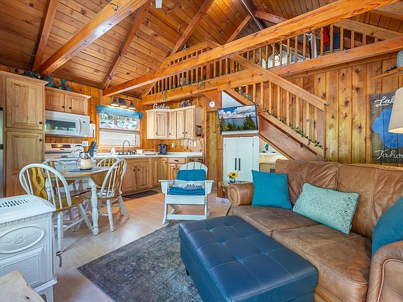 Main living area, dining, kitchen with vaulted ceilings, knotty pine wood accents and gas stove.