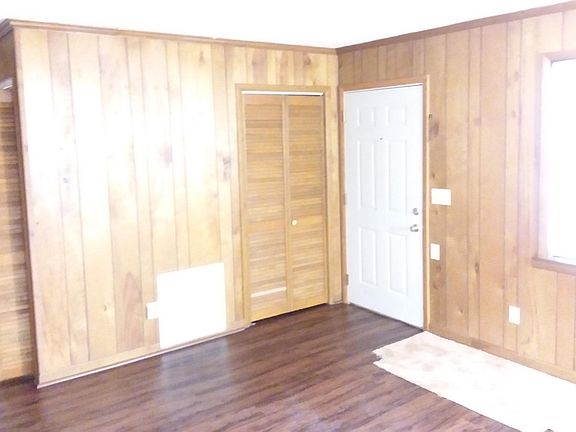 Interior view of the living room, front door, living room closet door and HVAC nook with the doors open.